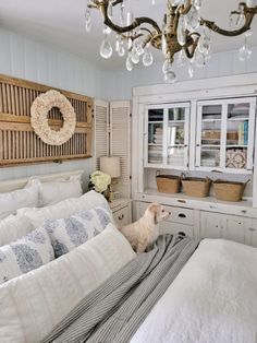 a dog sitting on top of a bed under a chandelier in a bedroom