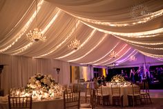 a banquet hall with white draping and chandelier draped over the tables