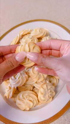 two hands reaching for some food on a plate