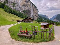 a wooden bench sitting in the middle of a lush green field next to a waterfall