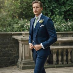 a man in a blue suit and white shirt is standing on a brick walkway with his hands in his pockets