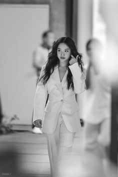 a woman in a white suit walking down the street