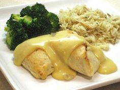 a white plate topped with chicken covered in gravy next to rice and broccoli