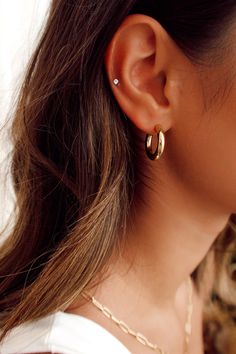 a close up of a woman's ear wearing gold earrings