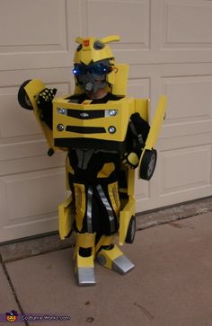 a yellow and black robot costume standing in front of a garage door