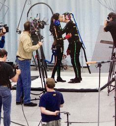 several people standing around in front of cameras on a stage with one woman kissing the camera