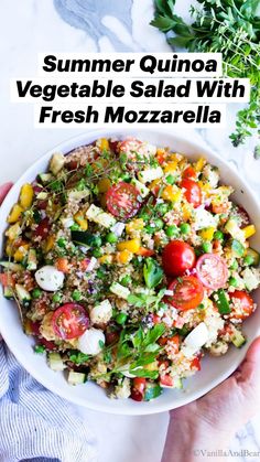 a white bowl filled with quinoa salad and topped with tomatoes, lettuce,