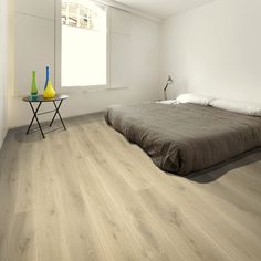 a bed sitting in the middle of a bedroom next to a table with two vases on it