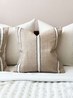 three pillows on top of a bed with white and black linens, one in the middle