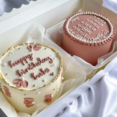 two birthday cakes in a box with pink frosting