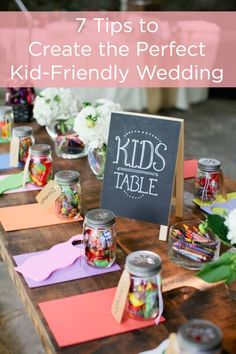 there is a sign that says kids table on the table with flowers and other items