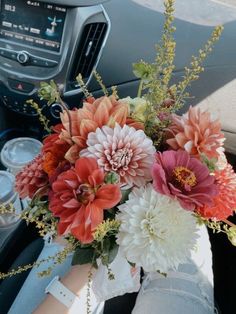 a bouquet of flowers sitting in the center of a car's dash board console