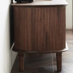 a wooden cabinet sitting next to a wall with a clock on it's side