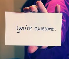 a person holding a piece of paper with the words you're awesome written on it