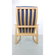 a wooden chair with blue and yellow stripes on it's back end, sitting in front of a white wall