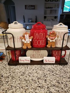 three christmas cookie jars and two gingerbread cookies are on a shelf in the kitchen