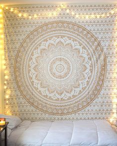 a bed with a large tapestry hanging on the wall next to candles and some lights