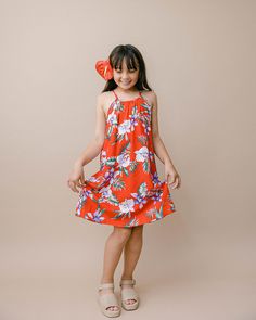 Add some flare to your little one's wardrobe with our Halter Dress. It's the ideal flowy & loose-fitting dress to give your mini the freedom to explore & play in style! Featuring adjustable straps that tie in the back, this gives you the option to alter the length by a few inches, allowing you to keep this dress for your mini just a little big longer as they continue to grow. Hoping to get a complimenting dress or shirt for the rest of the family? Our Matching Outfits Collection is your one-stop shop for everyone big and small on your list! Filled with vibrant orchid flowers & hints of palm leaves, our New Orchid design embodies the beauty & charm of Hawaii. This romantic print will make you fall in love across 2 colorways: black & red. * 100% Rayon * Offering 6M through size 12. * Knee le Playful Orange Beach Dress, Playful Red Dress For Vacation, Playful Red Dresses For Vacation, Summer Beach Twirl Dress, Playful Red Vacation Dress, Playful Red Sundress For The Beach, Casual Sleeveless Twirl Dress For Beach, Girls Halter Dress, Shirt Girl