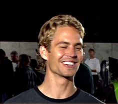 a man smiling while standing in front of a crowd