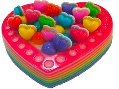 there is a heart shaped cake with many hearts on the top and bottom, as well as rainbow colored candies