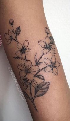 a black and white flower tattoo on the right arm, with leaves in blooming