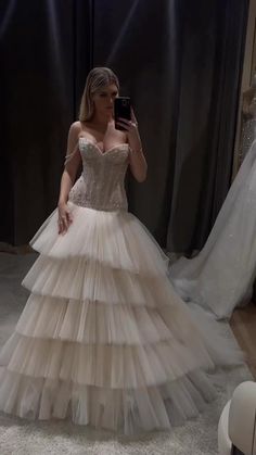 a woman in a wedding dress taking a selfie with her cell phone while she is dressed up