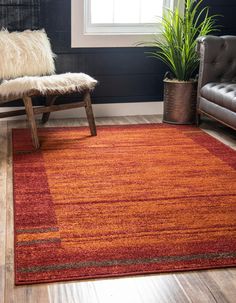 a living room with an orange rug and leather chair next to a plant in the corner