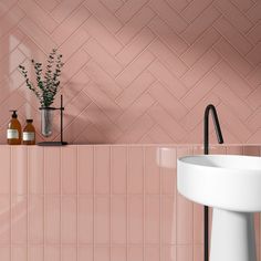 a white sink sitting next to a pink tiled wall