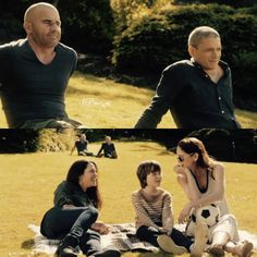 three people sitting on the grass with one person holding a soccer ball in front of them