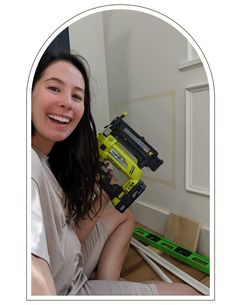 a woman sitting on the floor holding a drill