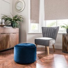 a chair and ottoman in a room with wood flooring, window blinds and a clock on the wall