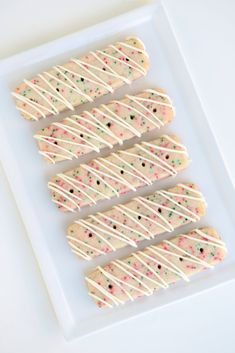 white chocolate covered cookies with sprinkles on a plate