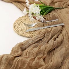 a table topped with a fork and knife next to a vase filled with white flowers