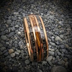 a wedding band with wood inlays and black diamonds on top of some rocks