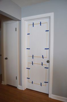 an open door with blue tape taped to it and the room is painted in white