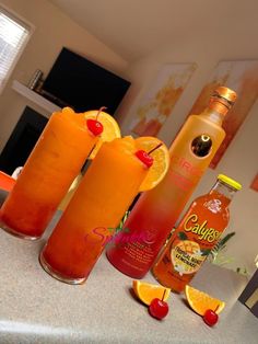 three orange drinks sitting on top of a counter