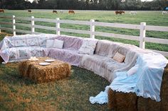 a large couch sitting on top of a lush green field next to a white fence