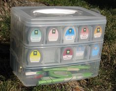 a plastic container filled with lots of different types of markers and scissors next to a tree