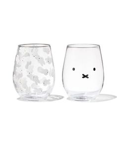 two glasses with faces on them sitting next to each other, one is clear and the other has black dots