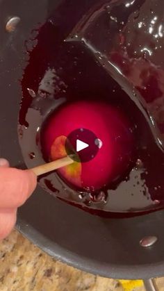 a person is stirring red liquid in a pot with a wooden spoon to stir it