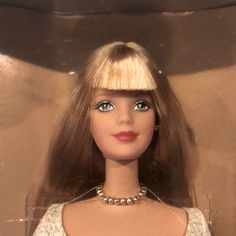 a barbie doll with blonde hair wearing a white dress and pearls on her neckline