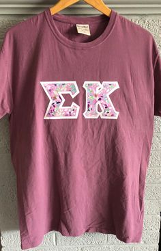 a t - shirt with the letter xo on it hanging up against a wall