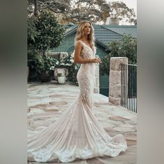 a woman standing in front of a house wearing a wedding dress