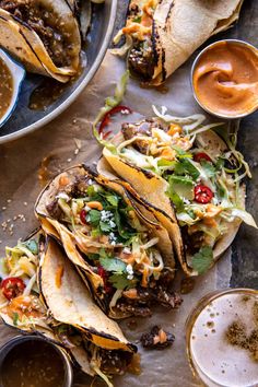 three tacos on a table with sauces and condiments