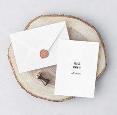 two envelopes sitting on top of a piece of wood next to a wax stamp