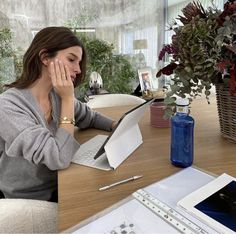 a woman sitting at a desk with her hand on her face while looking at papers