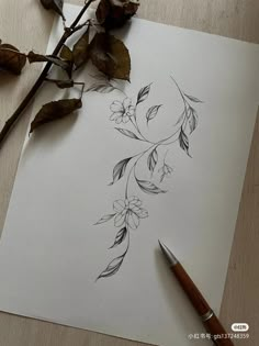 a drawing of flowers on paper next to a pen and some dried up branches with leaves