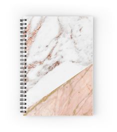 a spiral notebook with pink marble and gold foil on the cover, sitting on a white surface