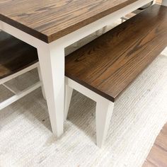 a wooden table with two benches sitting on it's sides next to a rug