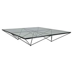 a glass and metal coffee table with geometric design on the top, against a white background